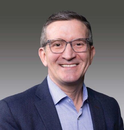 Smiling man in glasses and suit jacket.