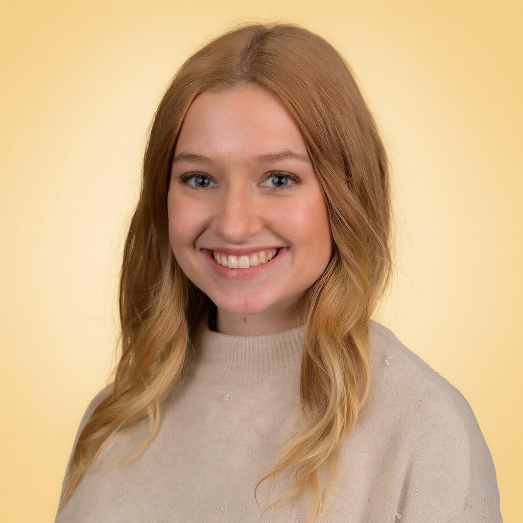 Smiling person with long hair, beige sweater.